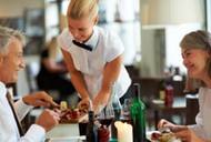 Hospitality - Waitress serving dinner to couple