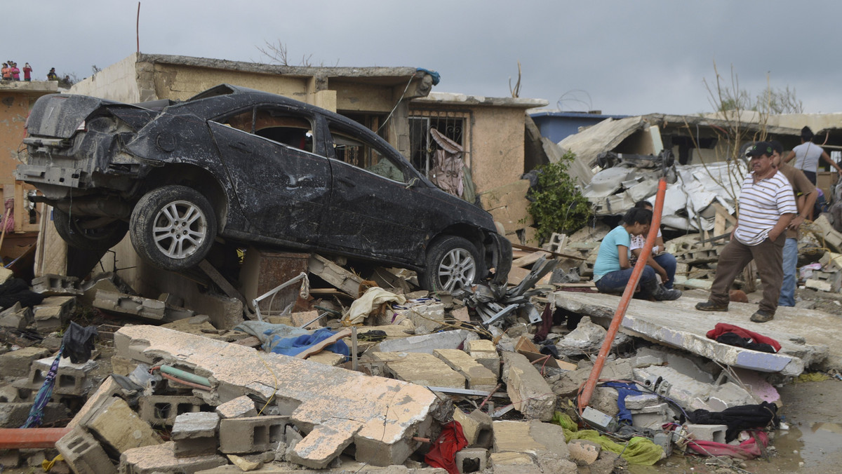 Residents stand outside their damaged house after a tornado hit the town of Ciudad Acuna