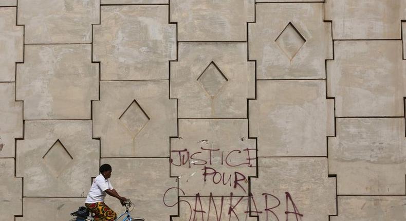 A woman rides a bicycle past graffiti reading Justice for Sankara in Ouagadougou, Burkina Faso, December 4, 2015. Picture taken December 4, 2015. REUTERS/Joe Penney