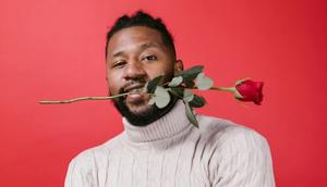 Man in white turtleneck sweater holding red rose [Image Credit: RDNE Stock Project]