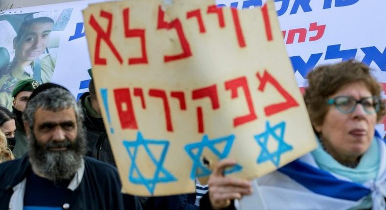 An Israeli woman holds a poster reading in Hebrew: We never abandon soldiers as she demonstrates outside the defence ministry in Tel Aviv on January 4, 2017, in support of Israeli soldier Elor Azaria, who shot dead a wounded Palestinian assailant