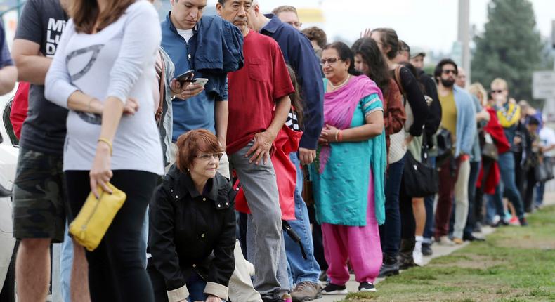 A woman kneels while waiting in line at an early voting polling place in Los Angeles.