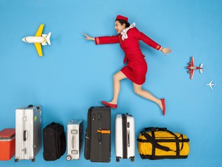 Flight attendant jumping over row of luggage