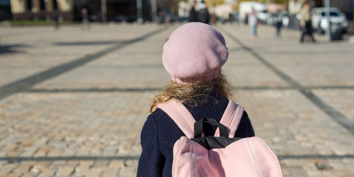 Stylish little girl with a backpack, in a coat and french beret run to school.