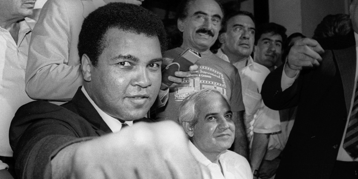 A smiling Muhammad Ali shows his fist to reporters during an impromptu press conference in Mexico City July 9, 1987.