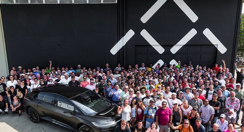 Attendees pose with the Faraday Future FF91 at the company's new manufacturing site in Hanford, CA.