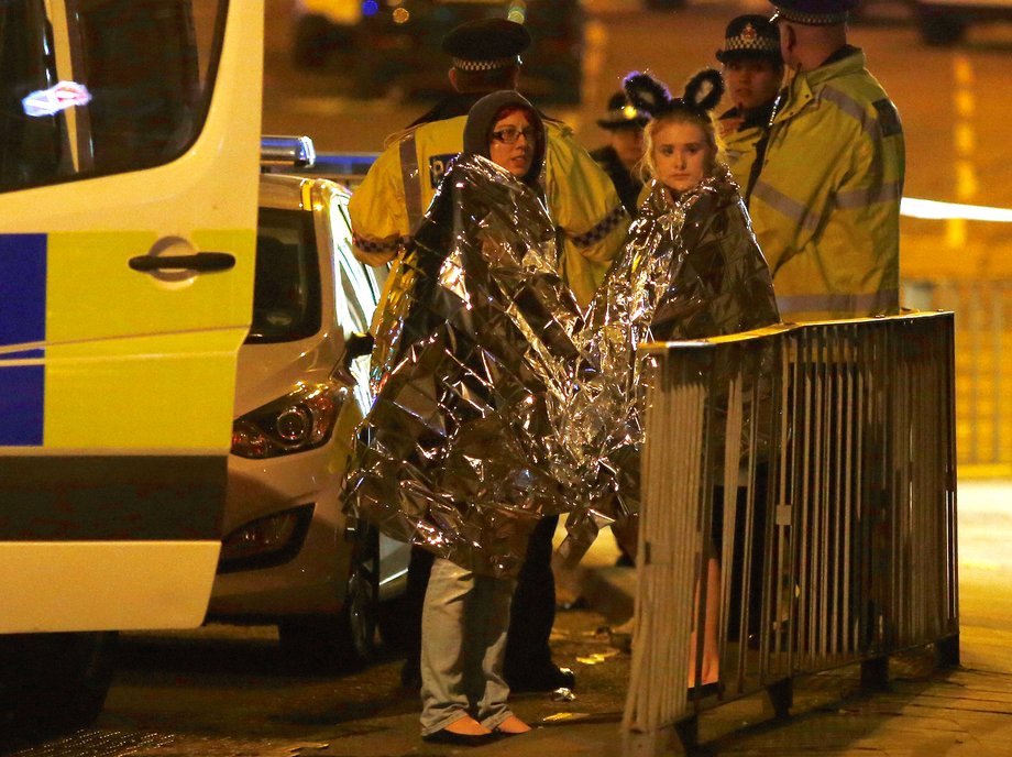 Two women wrapped in thermal blankets stand near the Manchester Arena, where U.S. singer Ariana Grande had been performing, in Manchester.