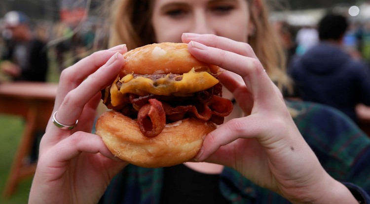 Hamburgert fogyasztó nő egy San Francisco-i zenei fesztiválon