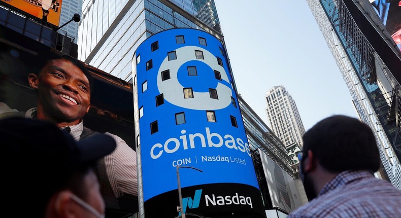 People watch as the logo for Coinbase Global Inc, the biggest U.S. cryptocurrency exchange, is displayed on the Nasdaq MarketSite jumbotron at Times Square in New York, U.S., April 14, 2021.
