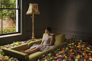 Woman sitting on sofa surrounded by flowers