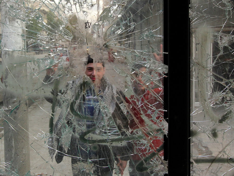 Boys are pictured through a broken windshield as they stand on a street in Aleppo February 28, 2013. R
