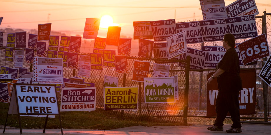 A woman passes by political campaign signs in Winston-Salem, North Carolina.