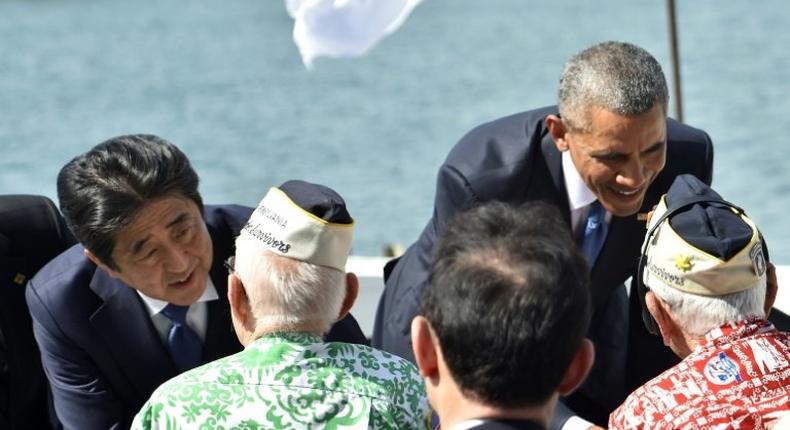 US President Barack Obama (R) and Japanese Prime Minister Shinzo Abe greet veterans at Kilo Pier overlooking the USS Arizona Memorial at Pearl Harbor in Honolulu, Hawaii on December 27, 2016