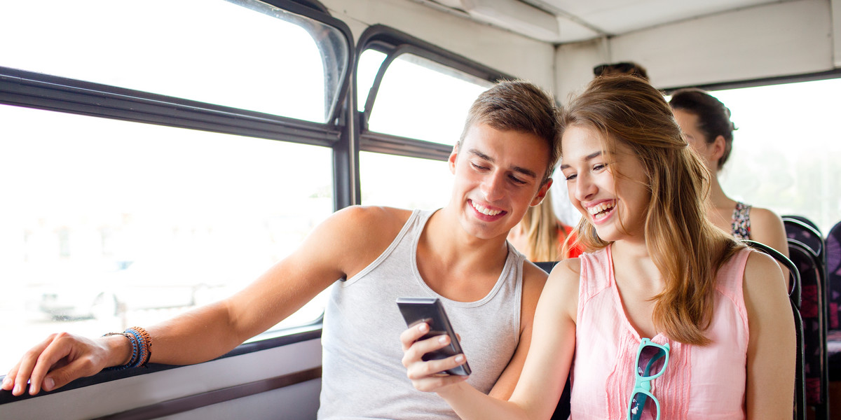 Uśmiechnięta para podróżuje autobusem