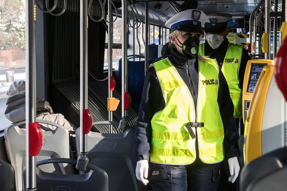 Funkcjonariusze policji w Krakowie podczas kontroli liczby pasażerów podróżujących autobusami.