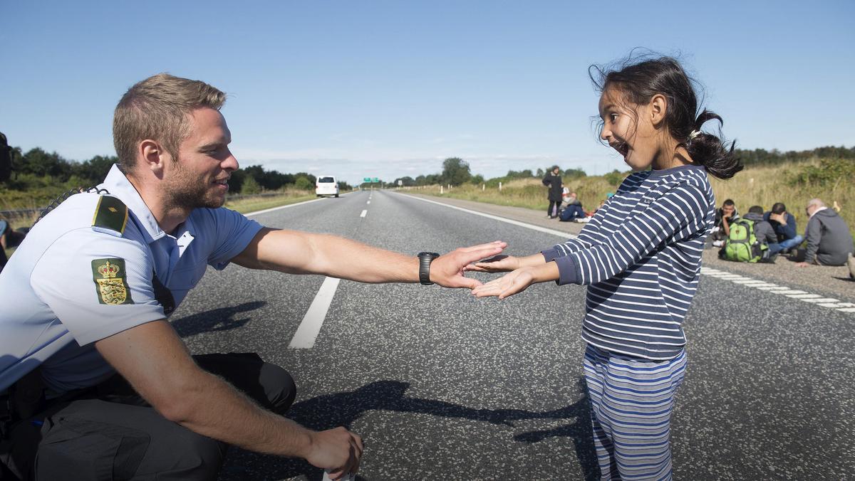 A Danish policeman plays with a migrant girl at the E45 freeway north of Padborg