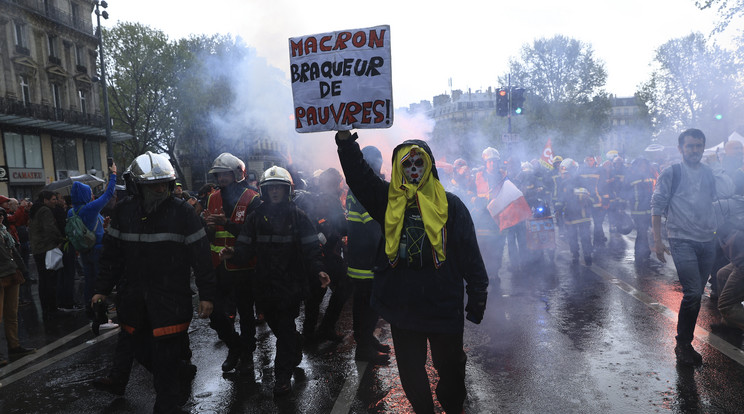 Mentőalakulatok dolgozói és egy tiltakozó táblát tartó férfi részt vesz a munka ünnepe alkalmából rendezett felvonuláson Párizsban/Fotó:MTI/AP/Aurelien Morissard