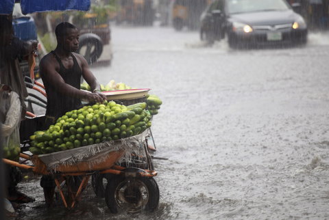 File Photo: A man arranges fruits in a wheelbarrow along a flooded street in Lagos, October 8, 2012. REUTERS/Akintunde Akinleye