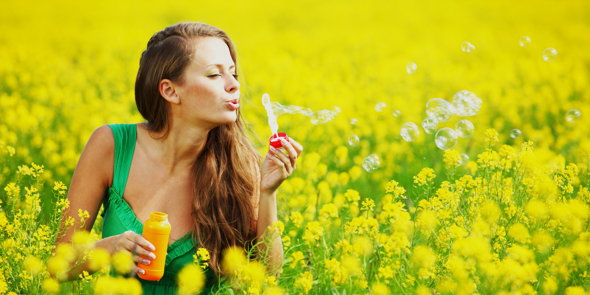 Kobieta z bańkami mydlanymi na polu z kwiatami