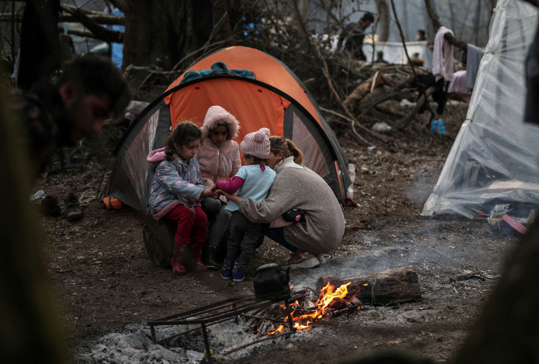 Uchodźcy siedzący przy ognisku niedaleko rzeki Ewros. Edirne, Turcja, 4 marca 2020