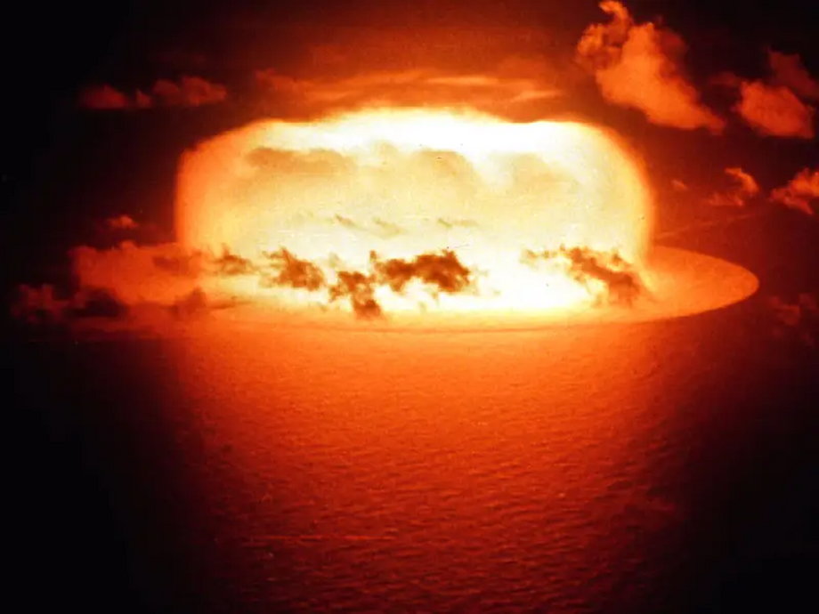 Błysk próbnej eksplozji bomby atomowej odbija się w wodach atolu Enewetak 30 maja 1956 r.  