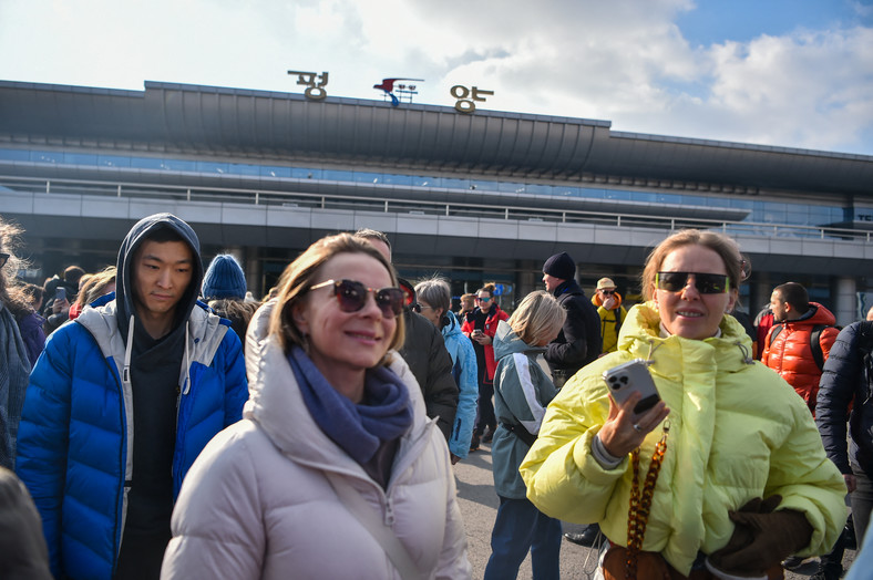 Grupa rosyjskich turystów wychodzi na zewnątrz po przybyciu na międzynarodowe lotnisko w Pjongjangu w dniu 9 lutego 2024 r.