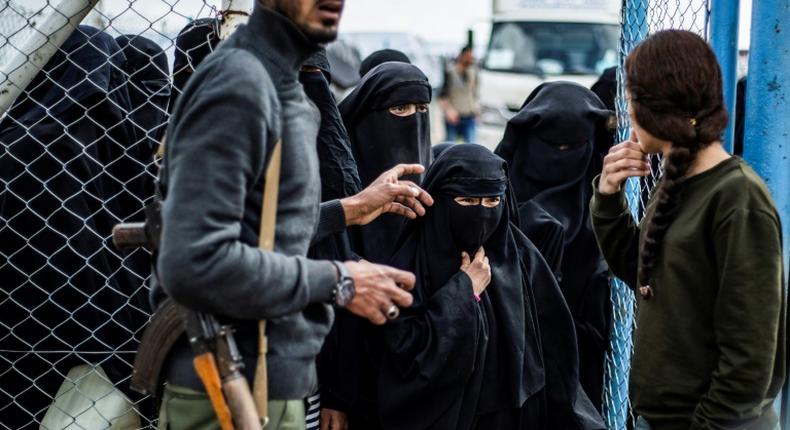 Members of the Syrian Democratic Forces stand guard over veiled women in al-Hol camp in northeastern Syria, which houses relatives of Islamic State group members