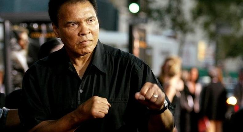 Boxing legend Muhammad Ali (R) jabs at photographers while arriving at the Orpheum Theatre for the premiere of the film Collateral in Los Angeles in this August 2, 2004 file photo. REUTERS/Robert Galbraith/File Photo