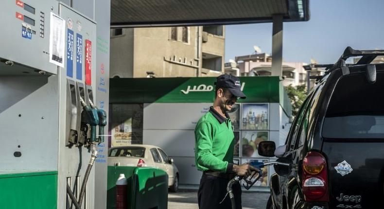 An Egyptian worker fills a customers tank as cars queue at a petrol station in the capital Cairo on November 4, 2016