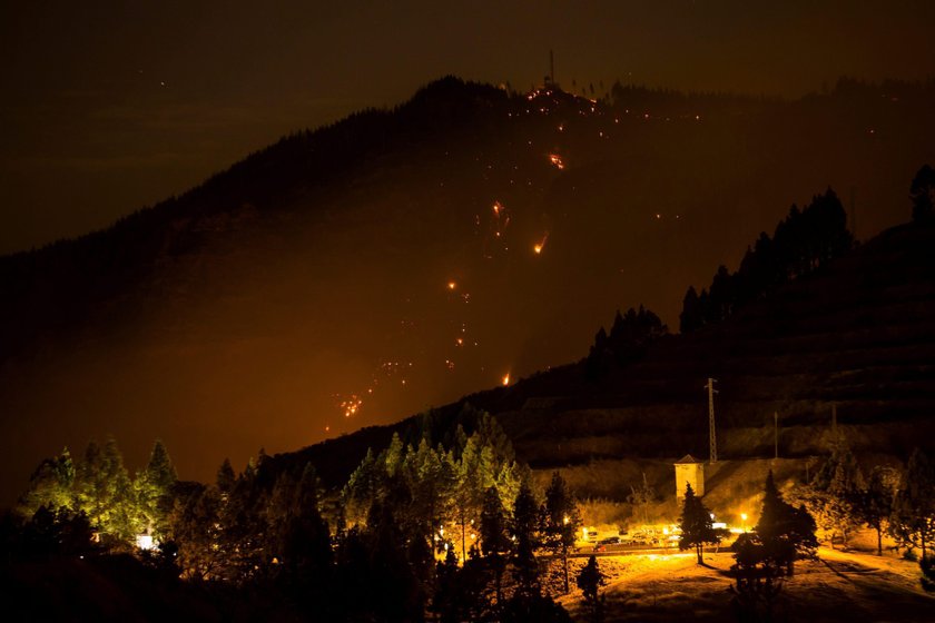 Flames and smoke from a forest fire are seen in the village of Valleseco