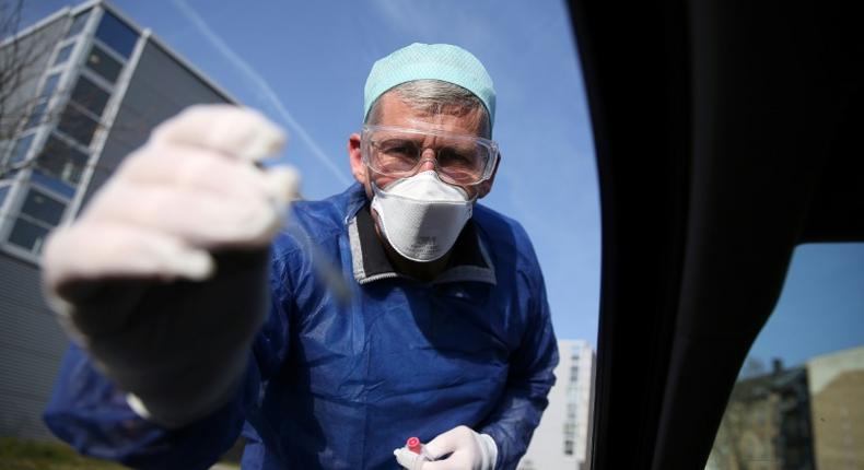 German doctor Michael Grosse takes a sample from a car driver at a drive-through testing point for the coronavirus in Halle, eastern Germany