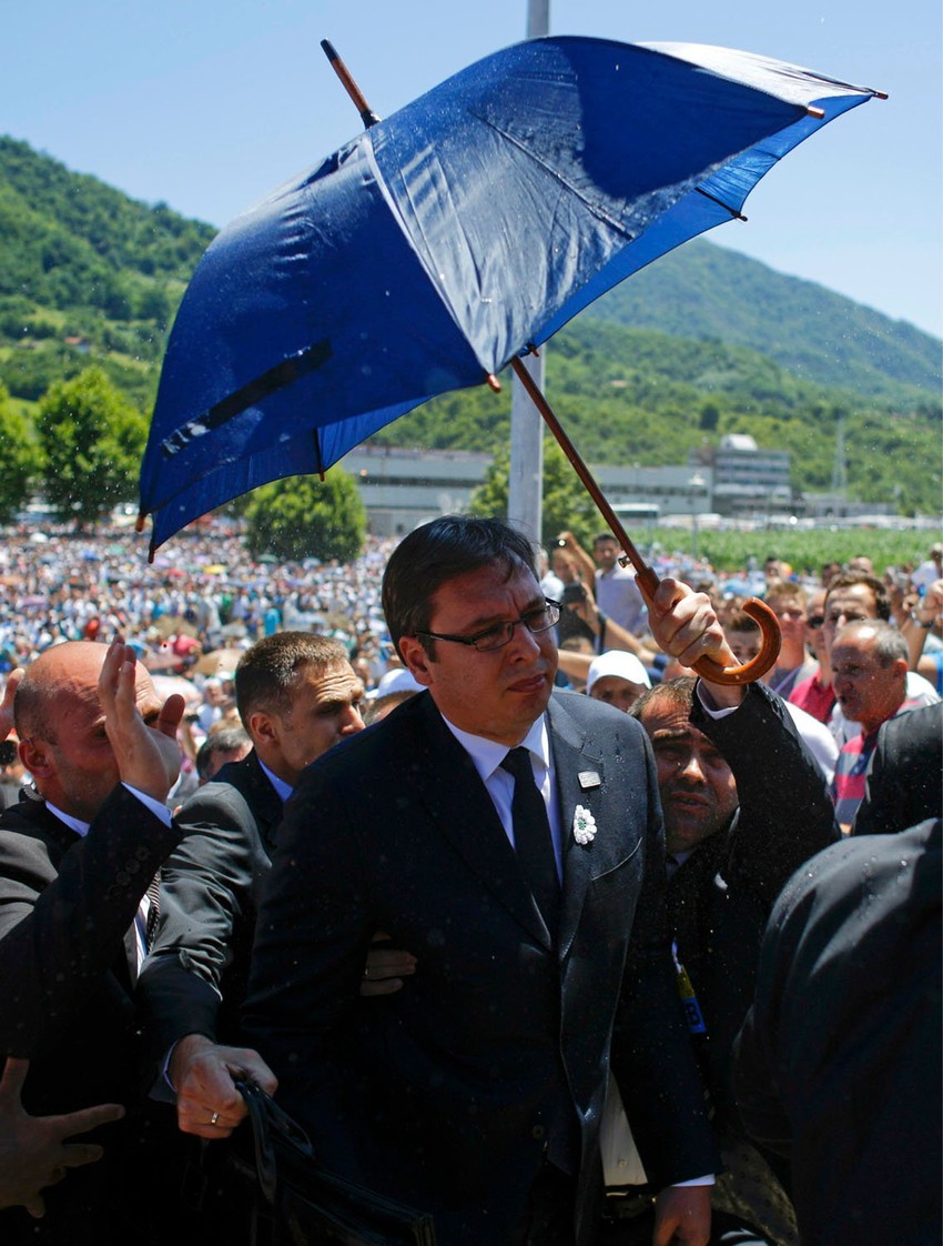 Vučića izvode s komemoracija štiteći ga kišobranom