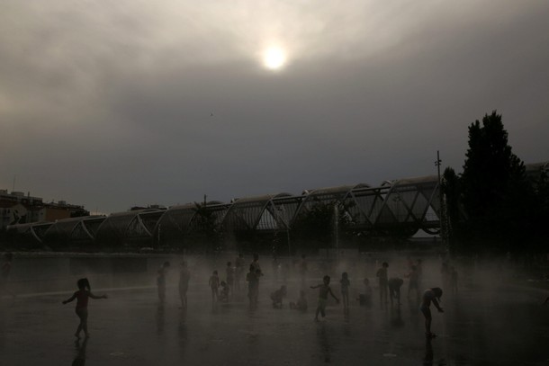 Children play as they cool down in a fountain beside Manzanares river during a heatwave in Madrid