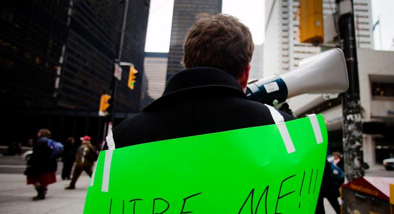 Lukas Stewart, with a sign strapped to his back, uses a megaphone to attract the attention of potential employers as he hands out resumes on Bay Street in the financial district in Toronto, March 5, 2009.