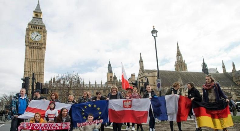 Demonstrators with national flags including that of Poland (centre) pose in front of Big Ben in London during a Flag Mob rally on February 20, 2017 in support of migrants in the UK