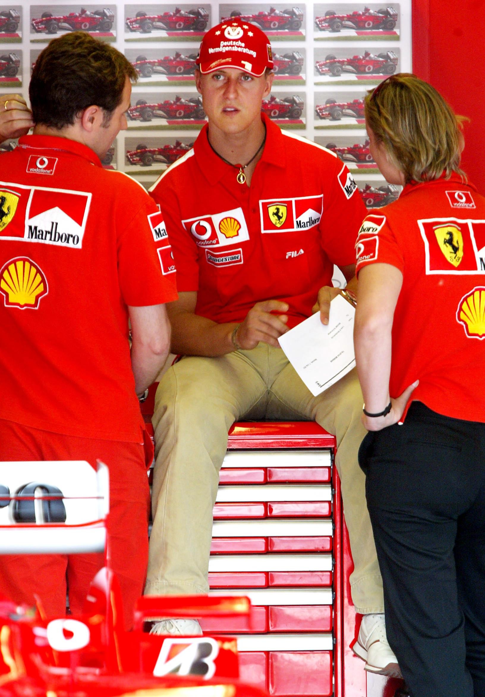 Bývalý majster sveta pretekov F1 Michael Schumacher debatuje s kolegami z Ferrari v garáži na okruhu Gillesa Villeneuveva v Montreale 12. júna 2003.