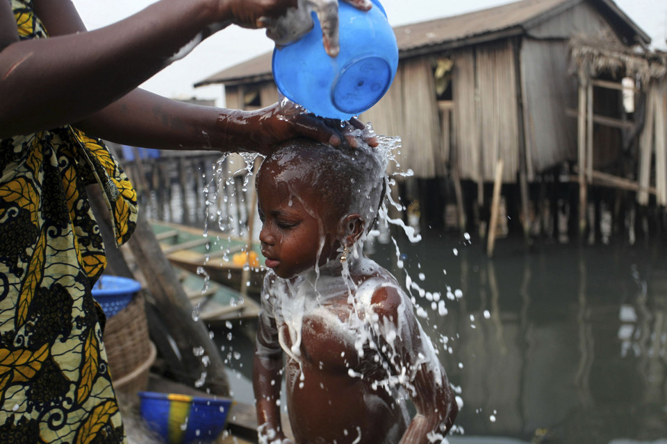A woman bathes her child in front of a stilt house in the Makoko fishing community in Nigeria's commercial capital Lagos