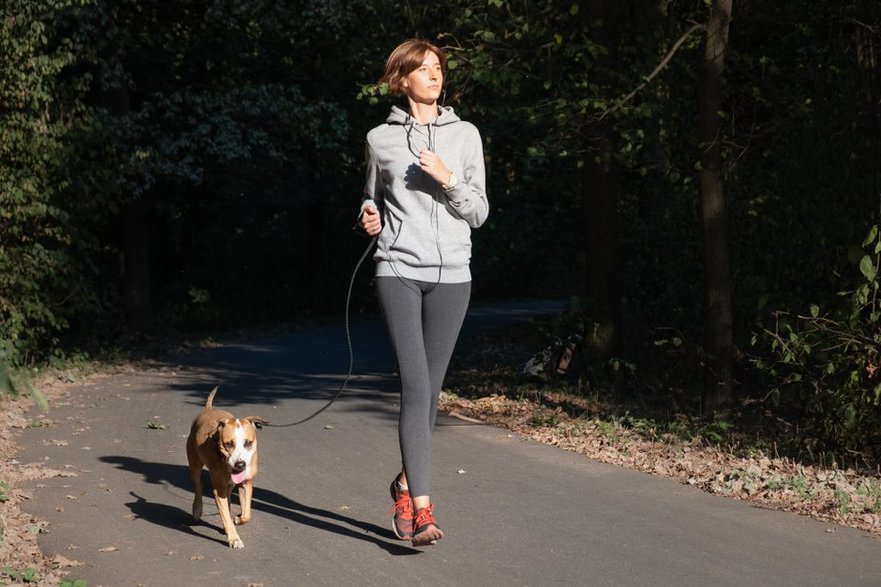 woman-jogging-with-dog-in-a-park-young-female-person-with-pet-doing-running-excercise-in-the-forest-1024x683