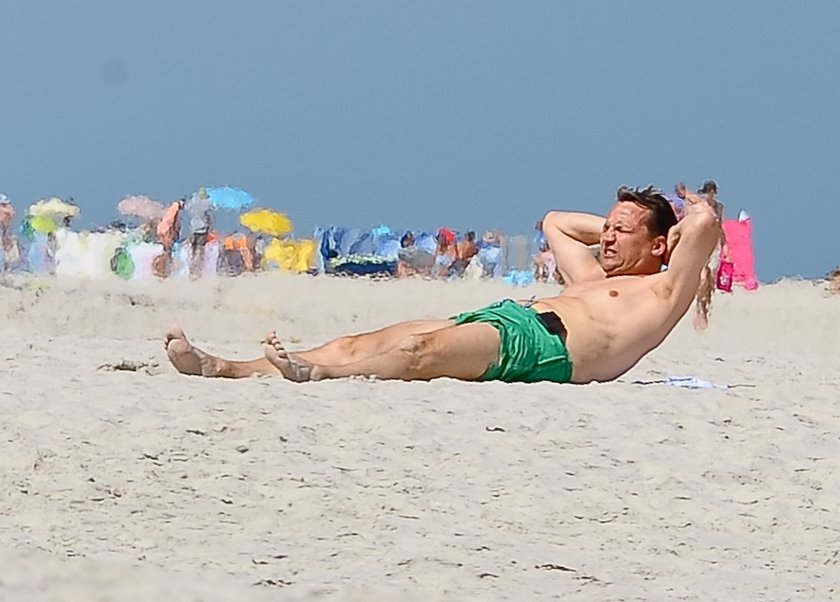 Radosław Sikorski na plaży ćwiczy brzuszki 