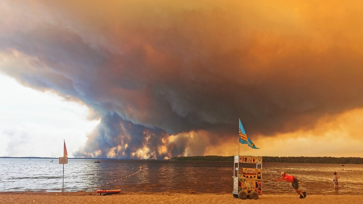 Posetioci plaže odmaraju se na plaži Mučik na obali jezera Lakano u Lakanou, na jugozapadu Francuske, dok požar besni u Žirondi, 24. jul 2026.