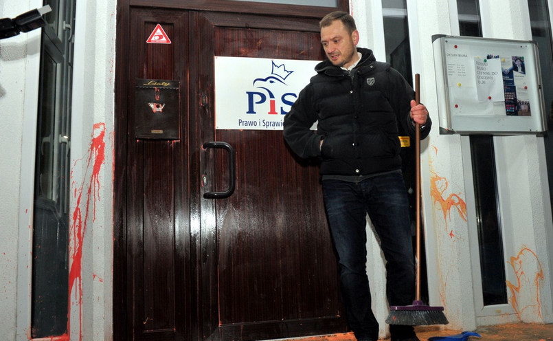 Poseł PO Sławomir Nitras zmywa farbę z drzwi biura PiS w Szczecinie