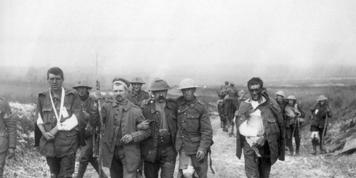 A German prisoner helps British wounded make their way to a dressing station near Bernafay Wood, following fighting on Bazentin Ridge, July 19, 1916, during the Battle of the Somme.