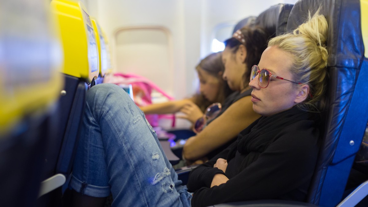 Tired lady napping on airplane.