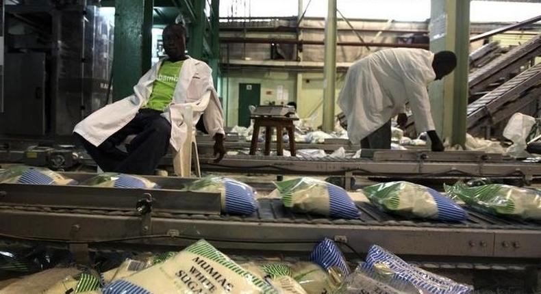 Workers arrange packets of sugar on a conveyor belt at the Mumias sugar factory in western Kenya