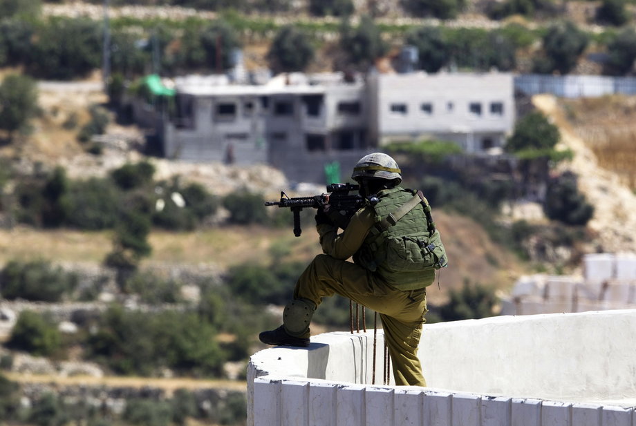 An Israeli soldier takes position during an operation to locate three missing teenagers, in the West Bank city of Hebron June 18, 2014.