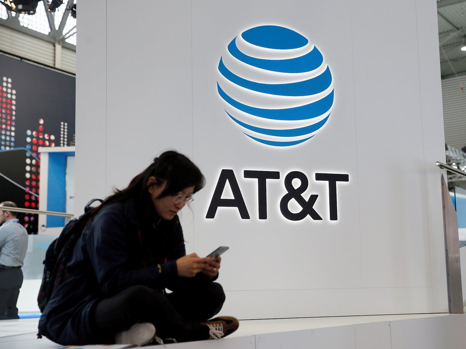 A woman looks at her mobile next to AT&T logo during the Mobile World Congress in Barcelona.