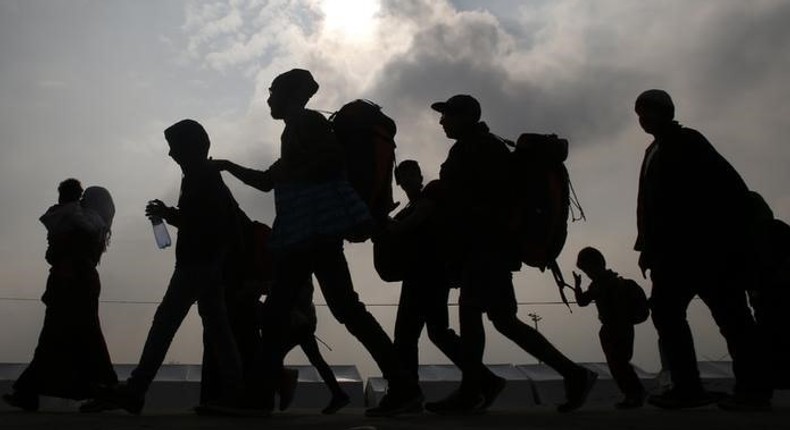 Migrants are silhouetted against the sky as they make their way to board buses in Nickelsdorf, Austria, October 6, 2015. REUTERS/Leonhard Foeger