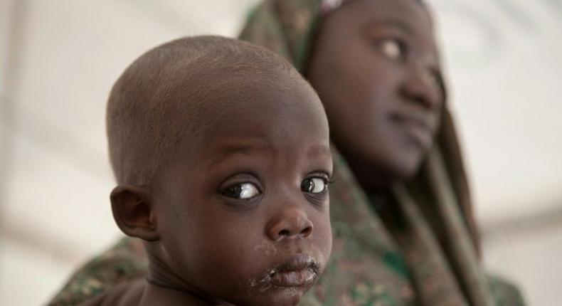 A mother holds her baby at a UNICEF Clinic near a camp for internallly displaced people (IDP) in Dikwa, northeast Nigeria on February 15, 2017