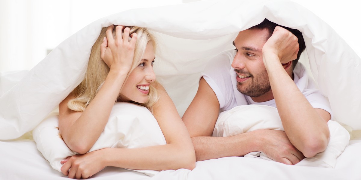 happy couple lying in bed and talking at home