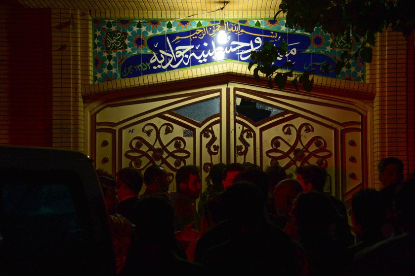 Afghan policemen and relatives inspect at the site of a suicide attack in Herat, Afghanistan